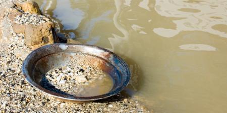 pan being used to fossick resting on the bank of a body of water