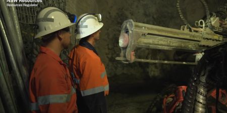 Workers inspect jumbo drilling rig